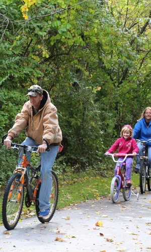 A family cycles down a leaf littered trail at the Slippery Elm Trail.